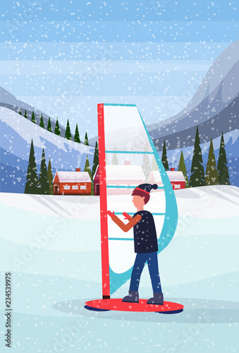 man windboarding windsurfing on snow over small village houses winter snowy mountains hills fir tree forest landscape background vertical flat photo