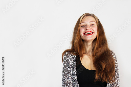 Girl with long brown hair and red lipstick is looking at camera and smiling. Light background with space for text