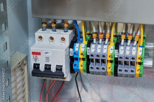 Modular circuit breaker and a number of terminals in the electrical Cabinet. Electrical wires or cables are connected to the switch and terminals. Reliable and modern power distribution.