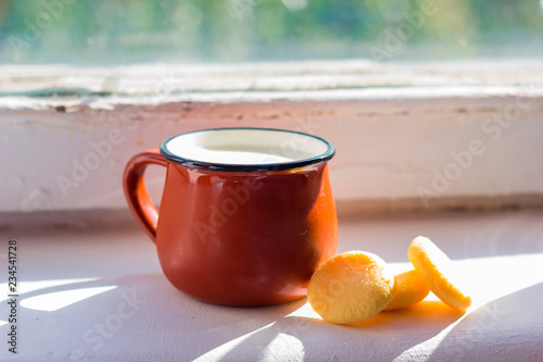 milk in small mug and kurt standing on windowsill in sunny day photo