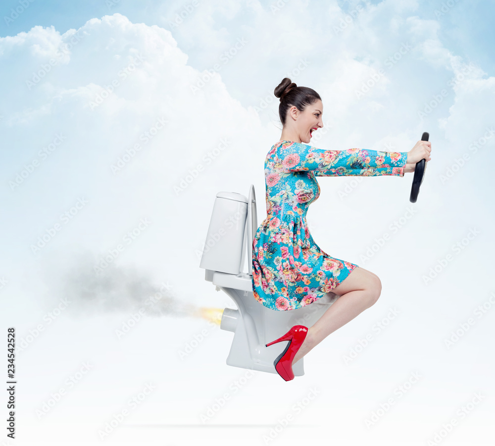 Funny girl in flower dress flying on the toilet with steering wheel.  Extraordinary transport concept Stock Photo | Adobe Stock