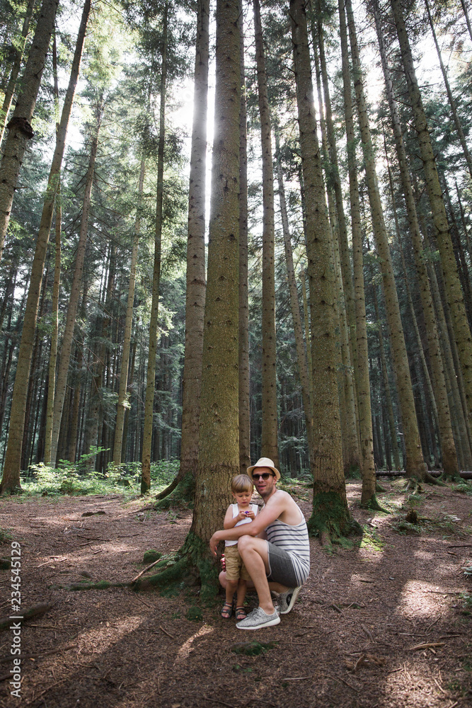 The happy young father standing with his cute little son in the forest The happy young father standing with his cute little son in the forest