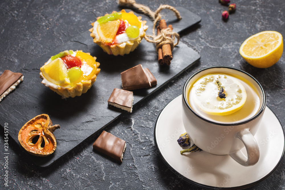 Fototapeta premium Cup of tea and cookies on black stone background.