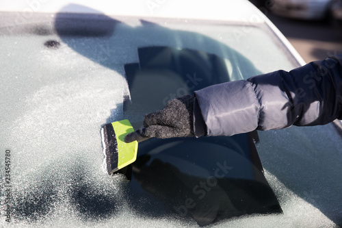 Hand in glove cleans window of the car from ice
