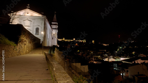 The historic waterfront cathedral Župnijska cerkev sv. Jurija in Piran (Slovenia) by night, with the city walls in the background