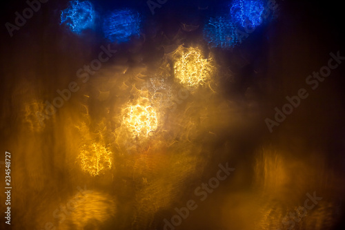 Abstract background blurred circles through wet glass  night rain outside the window.