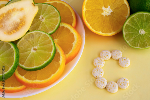 Letter C made from pills, colourful and fresh oranges, limes, guava. Vitamin from fruits concept.