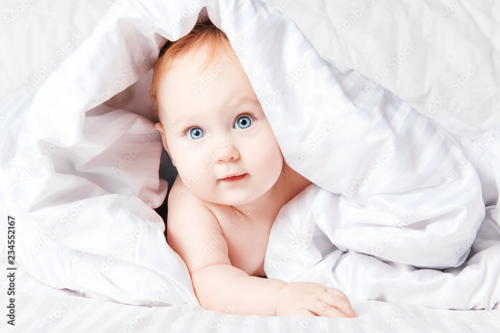 Cute little baby smiling under white blancket. Cute little baby smiling under white blancket.