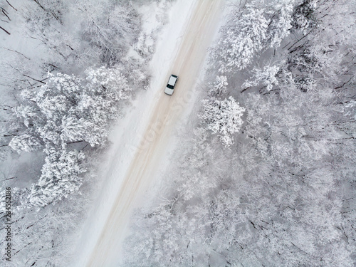 Blick von oben auf ein auto auf einer vereisten Straße im Winter bei Schnee © tronixAS