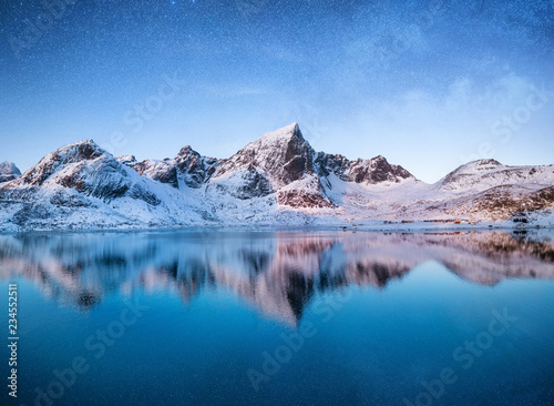 Mountains at the night time. Mountains and reflections on the water surface on Lofoten islands, Norway. Starry sky over the mountains. Winter landscape on Lofoten islands, Norway. 