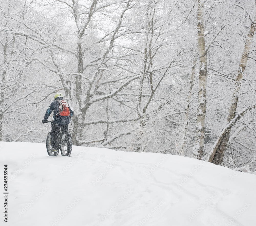 man riding with electric bicycle, e-bike, ebike, pedal on snowy road, during snow storm, blizzard, high mountain, end of winter, spring, cold, alps, adventure, isolated, fairy, Piedmont, Italy