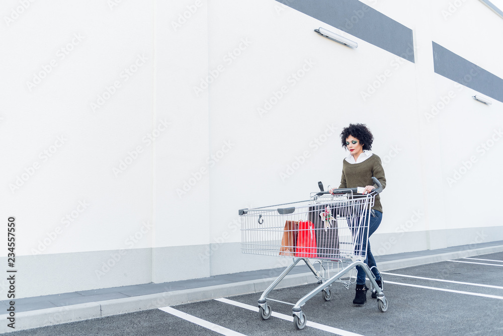 Young woman pushing a trolley outside of a mall Young woman pushing a trolley outside of a mall