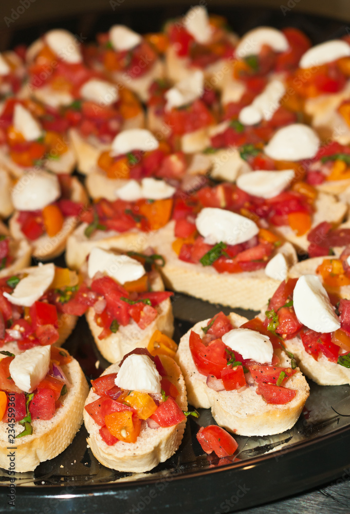 Top view, close up of appetizers of sliced french baguettes with chopped ripe tomatoes, scoop of soft cheeses, italian parsley, for a french wine tasting event