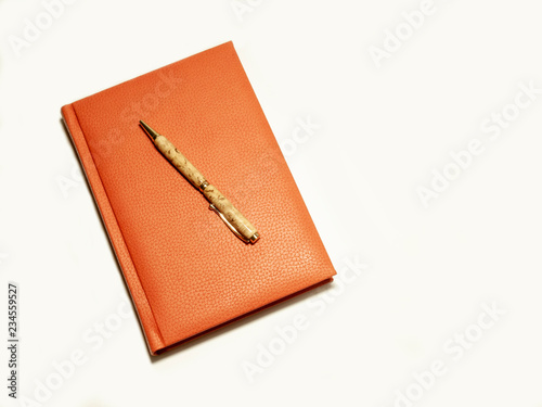 Orange notepad with a pen isolated.