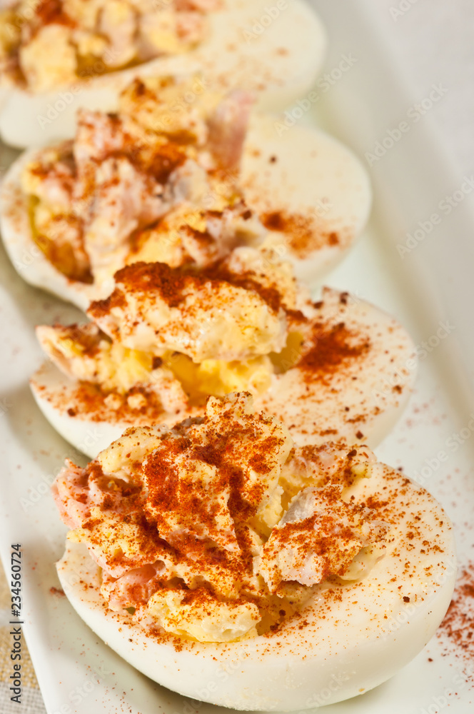 Top view, close up of  salmon deviled eggs with paprika on a white, rectangular plate