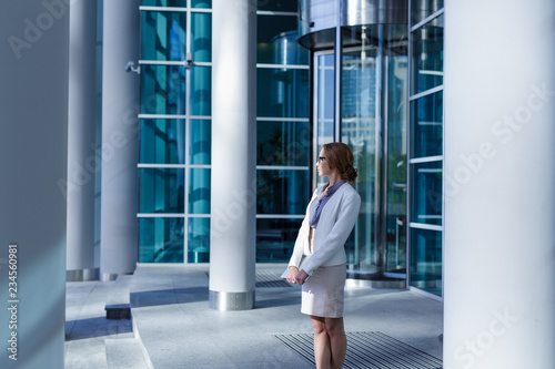 Fotografi Pretty business woman standing in front of revolving door