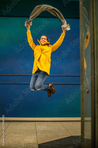 Junge Frau springt vor Freude in Ubahn Station mit Schal