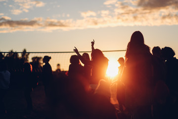 Sunset beach party dancers silhouettes near volleyball court