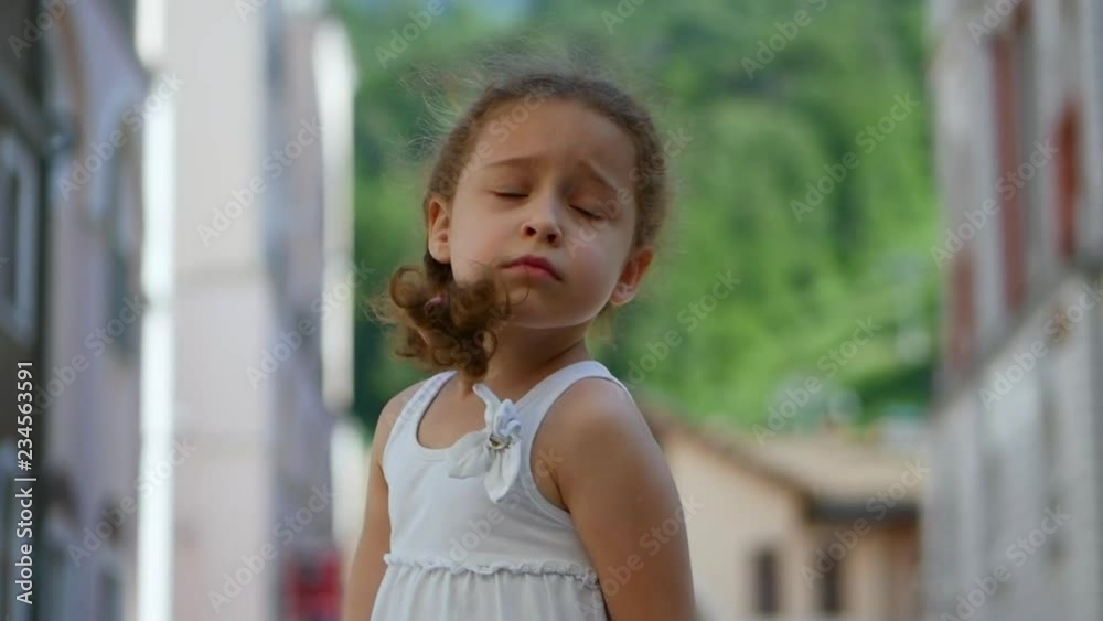 A sweet little curly girl with golden hair is sad and at the same time spinning in the dance and rotating in the street against the backdrop of the mountains. Average deceleration. A sweet little curly girl with golden hair is sad and at the same time spinning in the dance and rotating in the street against the backdrop of the mountains. Average deceleration.