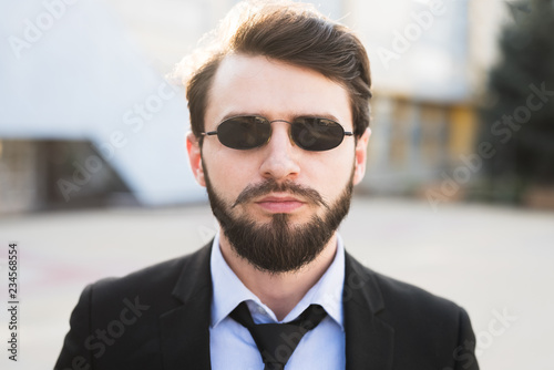 Portrait of bearded hipster with sunglasses dressed in suit.