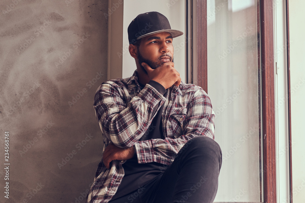 Naklejka premium Pensive African-American bearded man looking out the window.