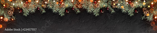 Christmas Fir branches with pine cones on dark holiday background with light. Xmas and Happy New Year theme. Flat lay, top view, wide composition