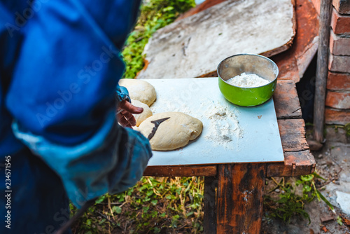 The woman in oversleeves cooks dough for home-made bread on open air photo