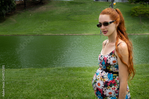 pregnant woman with lake and trees in the background © Marcos