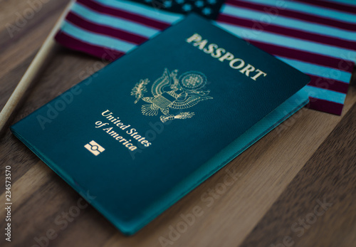 American flag next to passport of USA on wooden surface.