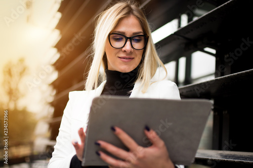 Business woman standing and typing on her tablet