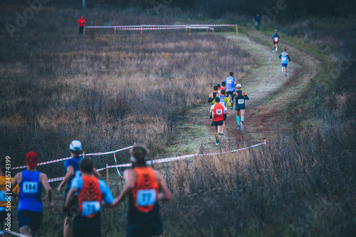 Group of professional cross country athletes running in competition in autumn nature. Sport or orienteering run concept