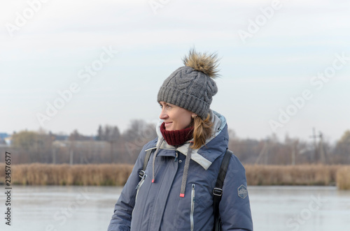Pretty girl having fun on the winter lake, waving hair, smiling. Snowy mountains and blue sky on the background.