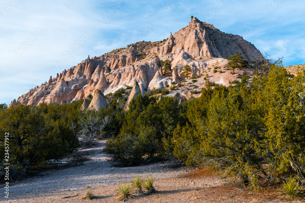 Naklejka premium Kolorowy czerwony szczyt skalny z licznymi formacjami skalnymi hoodoo w wieczornym świetle przy pomniku narodowym Kasha-Katuwe Tent Rocks w pobliżu Santa Fe w Nowym Meksyku