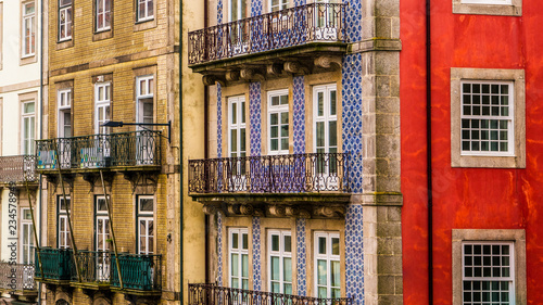 Fotografering Row of old, colorful buildings with ornate balconies and tiles line a street in
