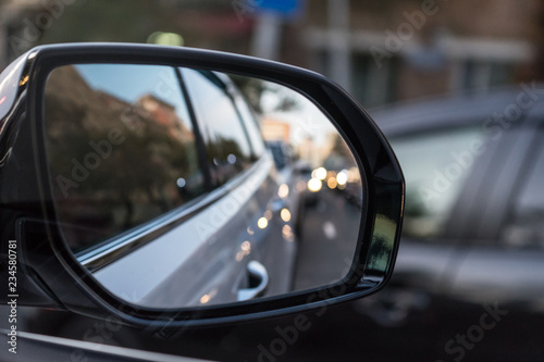 Evening background with car mirror reflecting the street © vvicca