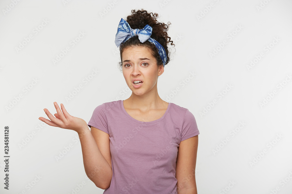 Portrait of annoyed female clenches teeth with irritation, raised her hand in misunderstanding or trying to bring something elementary, over white background. People and negative emotions concept Portrait of annoyed female clenches teeth with irritation, raised her hand in misunderstanding or trying to bring something elementary, over white background. People and negative emotions concept