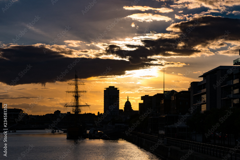 Dublin City skyline in silhouette at sunset, Ireland looking over River Liffey with buildings, famine ship and Dublin Spire