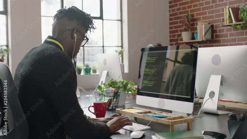 portrait african american man programmer coding network security software for startup company professional web developer typing code on computer screen listening to music in successful office 