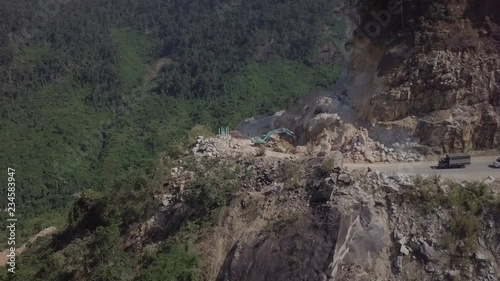 Aerial view of the excavator working on the serpentine road in Vietnam Dalat. Landslide. Vehicle trapped on traffic jam because of the rocks. 