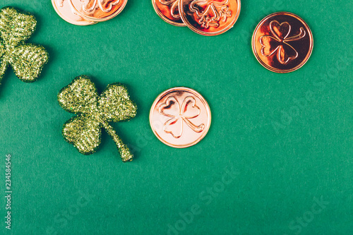 Glitter shamrocks and golden coins on green paper background. St Patricks day symbol. Irish National holiday concept