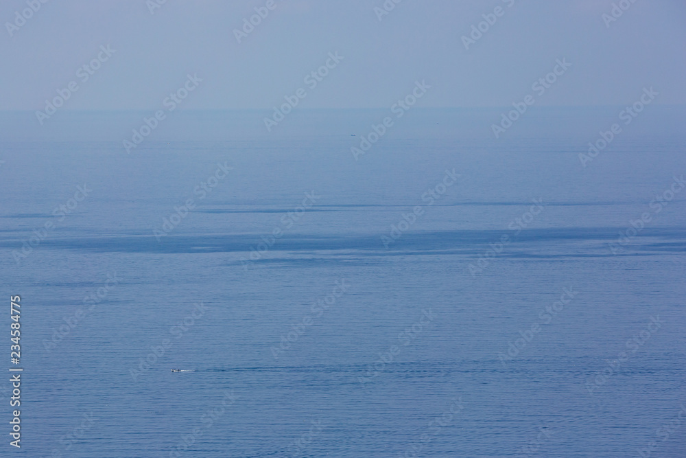 Abstract view of the ocean with a tiny motorboat moving across the surface
