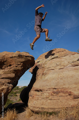 Young man leaping on high rock formations at Vazquez Rocks in California