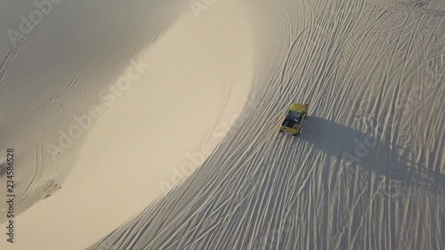 2K Aerial top view. Yellow jeep drives through the desert. Sand dunes in Vietnam