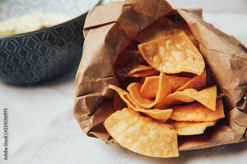 nachos and bowl with loaded queso. selective focus. Corn chips  nachos in a brown paper bag