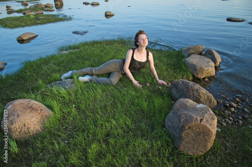 young woman lying in the grass on the shore near the water photo