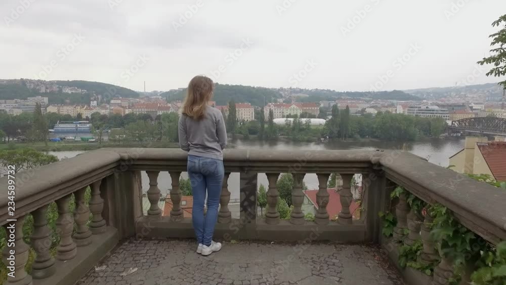 young woman is admiring city view from balcony on hill, camera is moving from back young woman is admiring city view from balcony on hill, camera is moving from back