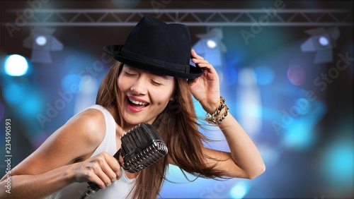Young woman wearing hat singing into microphone