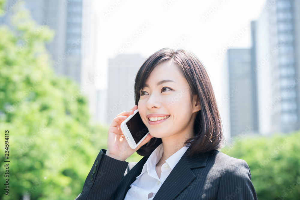 スマートフォンで通話するビジネスウーマン スマートフォンで通話するビジネスウーマン
