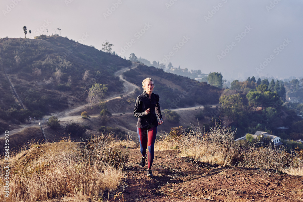 Fototapeta premium Beautiful Caucasian White Woman Runs on a Trail in the Morning Sunlight