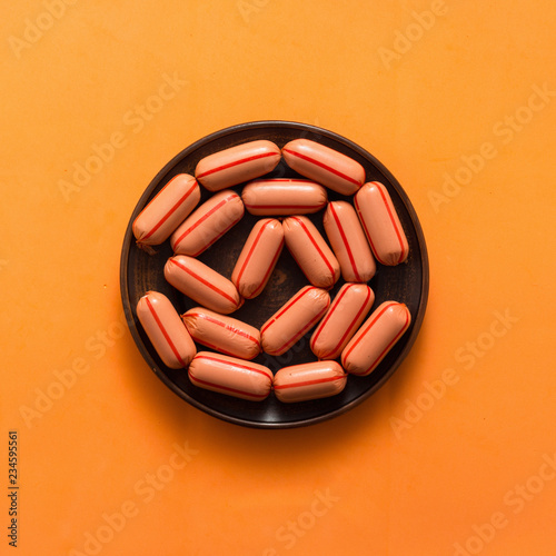 Raw sausages on orange background, top view, flat lay